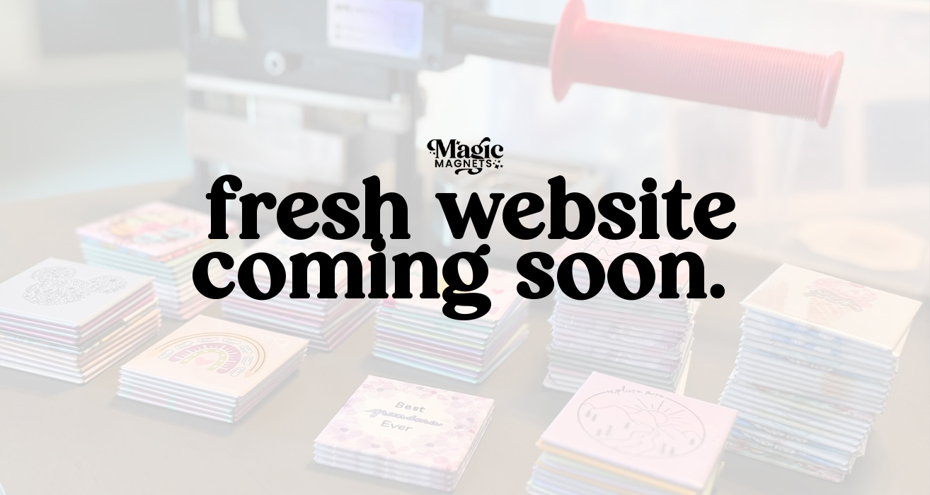 Stacks of colorful square magnets with a press machine in the background and text reading “Fresh website coming soon”
